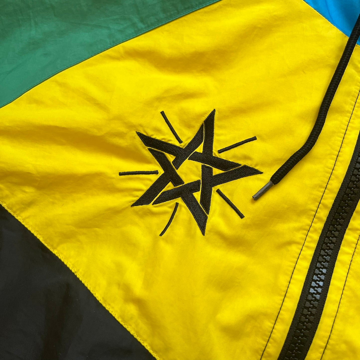 Nike Ethiopia Olympics 2008 Split Windbreaker is a performance jacket designed by Jarrett Reynolds for the Olympic collection. The jacket features a black lower section, yellow upper body, blue hood, green shoulder and red opposite shoulder. The chest is finished with an embroidered Nike logo and Ethiopia emblem. The jacket features a unique split construction that allows it to be unzipped along both sides and connected with other compatible jackets. Hidden inside, a small Ethiopia flags accent completes th