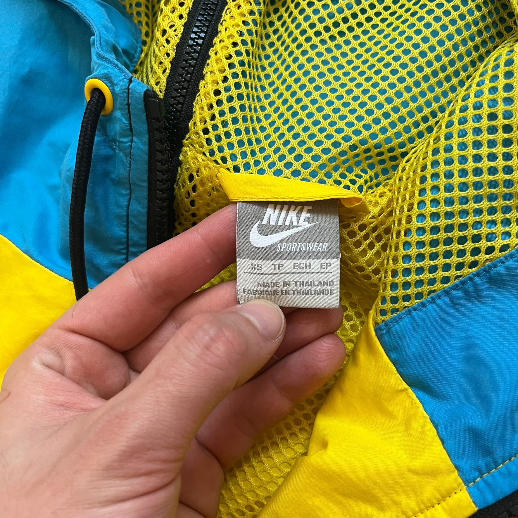 Nike Ethiopia Olympics 2008 Split Windbreaker is a performance jacket designed by Jarrett Reynolds for the Olympic collection. The jacket features a black lower section, yellow upper body, blue hood, green shoulder and red opposite shoulder. The chest is finished with an embroidered Nike logo and Ethiopia emblem. The jacket features a unique split construction that allows it to be unzipped along both sides and connected with other compatible jackets. Hidden inside, a small Ethiopia flags accent completes th