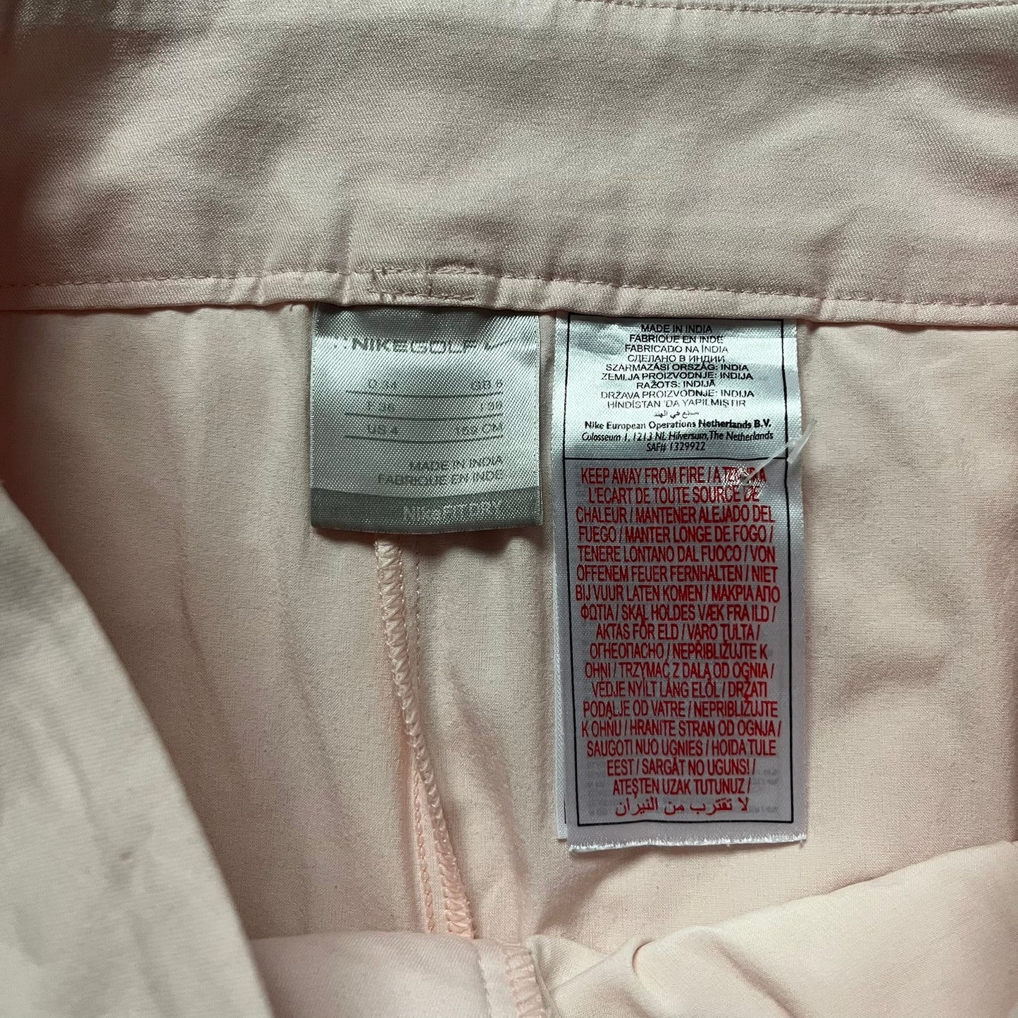 Nike Fit-Dry Light Pink Golf Skirt is a women’s golf skort with integrated inner shorts. The light pink skirt features belt loops at the waistband, front and back pockets, side cutouts for flexibility, and a button closure. A small embroidered Nike logo is placed at the back, maintaining a minimal design.