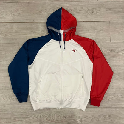 The Nike France Olympics 2008 Split Windbreaker made in a white, red, and navy color block representing France, it includes a red embroidered Nike logo and hidden French flags inside both pockets. It features a modular design by Jarrett Reynolds, allowing the jacket to split on both sides via dual zippers.