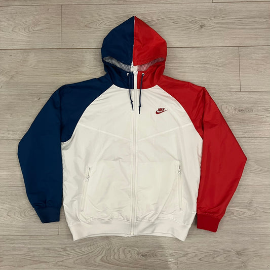 The Nike France Olympics 2008 Split Windbreaker made in a white, red, and navy color block representing France, it includes a red embroidered Nike logo and hidden French flags inside both pockets. It features a modular design by Jarrett Reynolds, allowing the jacket to split on both sides via dual zippers.