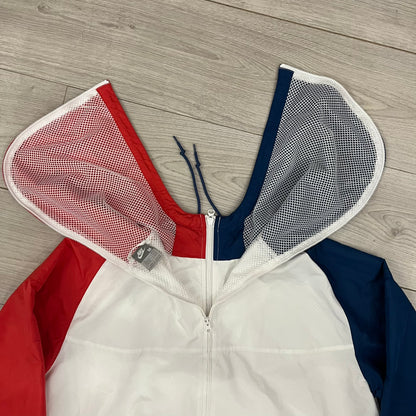 The Nike France Olympics 2008 Split Windbreaker made in a white, red, and navy color block representing France, it includes a red embroidered Nike logo and hidden French flags inside both pockets. It features a modular design by Jarrett Reynolds, allowing the jacket to split on both sides via dual zippers.