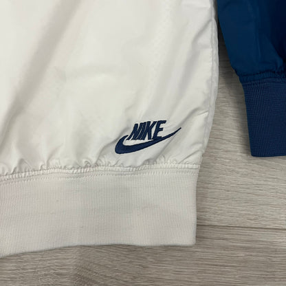 The Nike France Olympics 2008 Split Windbreaker made in a white, red, and navy color block representing France, it includes a red embroidered Nike logo and hidden French flags inside both pockets. It features a modular design by Jarrett Reynolds, allowing the jacket to split on both sides via dual zippers.