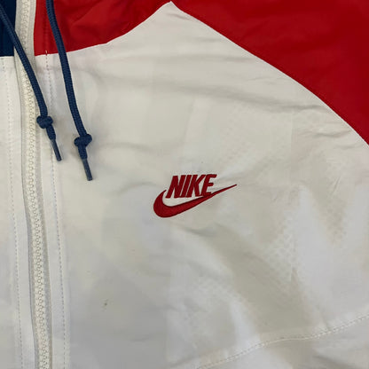 The Nike France Olympics 2008 Split Windbreaker made in a white, red, and navy color block representing France, it includes a red embroidered Nike logo and hidden French flags inside both pockets. It features a modular design by Jarrett Reynolds, allowing the jacket to split on both sides via dual zippers.