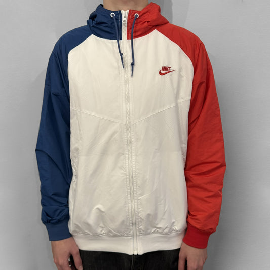 The Nike France Olympics 2008 Split Windbreaker made in a white, red, and navy color block representing France, it includes a red embroidered Nike logo and hidden French flags inside both pockets. It features a modular design by Jarrett Reynolds, allowing the jacket to split on both sides via dual zippers.