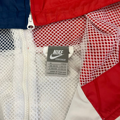 The Nike France Olympics 2008 Split Windbreaker made in a white, red, and navy color block representing France, it includes a red embroidered Nike logo and hidden French flags inside both pockets. It features a modular design by Jarrett Reynolds, allowing the jacket to split on both sides via dual zippers.