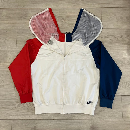 The Nike France Olympics 2008 Split Windbreaker made in a white, red, and navy color block representing France, it includes a red embroidered Nike logo and hidden French flags inside both pockets. It features a modular design by Jarrett Reynolds, allowing the jacket to split on both sides via dual zippers.