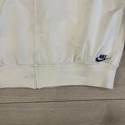 The Nike France Olympics 2008 Split Windbreaker made in a white, red, and navy color block representing France, it includes a red embroidered Nike logo and hidden French flags inside both pockets. It features a modular design by Jarrett Reynolds, allowing the jacket to split on both sides via dual zippers.