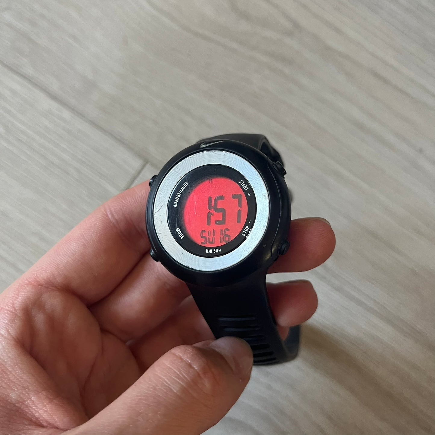 Nike Georg WK0010 digital watch with a bold red dial and black case accented by a silver aluminum bezel. Features include chronograph, alarm, time, and date functions with a 12-hour display and backlight. Water-resistant up to 50m with a durable black silicone strap.