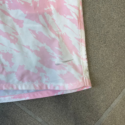 Nike Golf Pink & White Animal Print Skort features a white base with a pink animal-style camouflage pattern that gradually fades toward the lower section. It has built-in white shorts underneath, an embroidered Nike logo at the bottom corner, and pockets on both the front and back.

