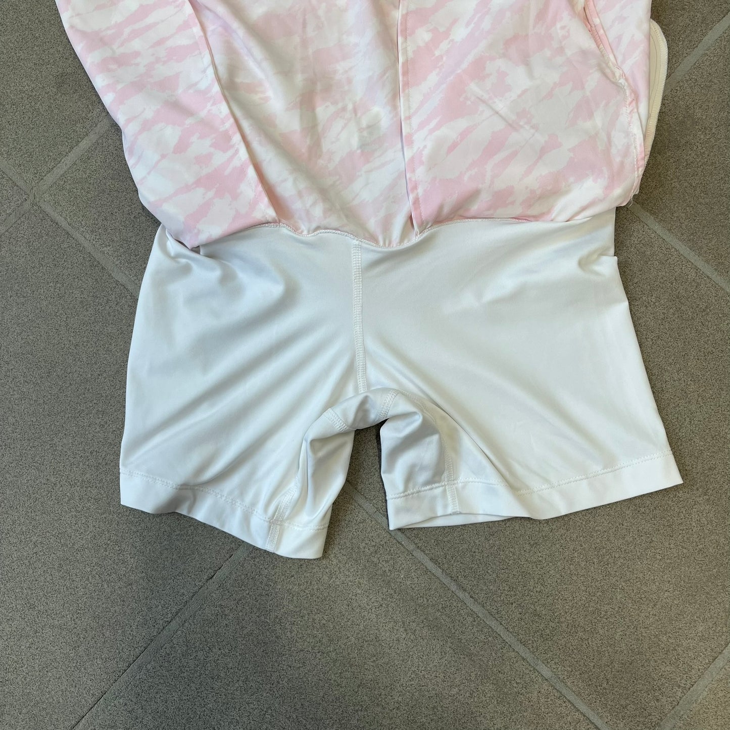 Nike Golf Pink & White Animal Print Skort features a white base with a pink animal-style camouflage pattern that gradually fades toward the lower section. It has built-in white shorts underneath, an embroidered Nike logo at the bottom corner, and pockets on both the front and back.
