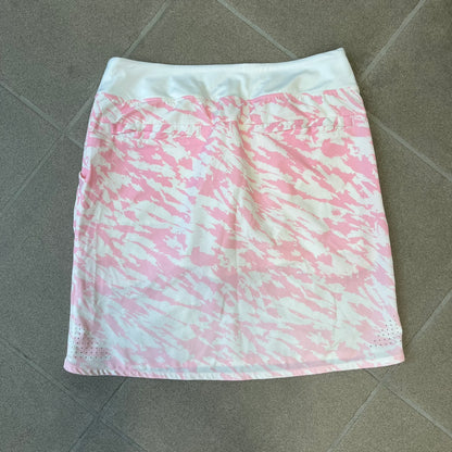 Nike Golf Pink & White Animal Print Skort features a white base with a pink animal-style camouflage pattern that gradually fades toward the lower section. It has built-in white shorts underneath, an embroidered Nike logo at the bottom corner, and pockets on both the front and back.
