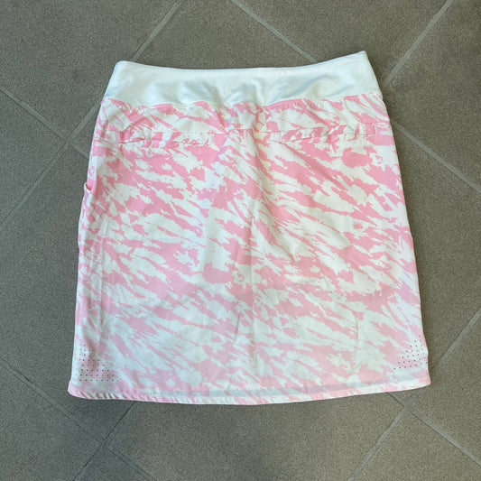Nike Golf Pink & White Animal Print Skort features a white base with a pink animal-style camouflage pattern that gradually fades toward the lower section. It has built-in white shorts underneath, an embroidered Nike logo at the bottom corner, and pockets on both the front and back.
