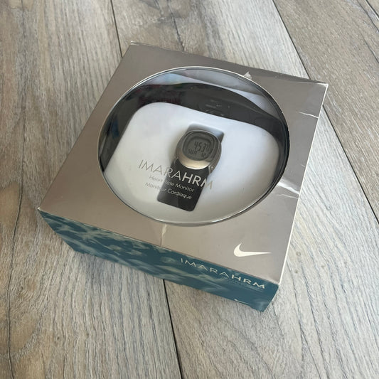 Nike Imara HRM SM0032 Digital Watch is a digital wristwatch featuring a silver case with gray-outlined display and a black rubber strap. The watch includes backlight functionality, multiple modes, and a chest heart rate monitor, with water resistance up to 59 meters. It comes with original box, papers, and a plastic store display.