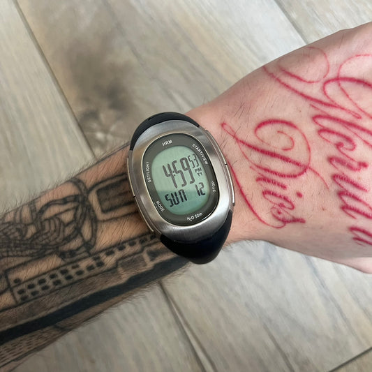 Nike Imara HRM SM0032 Digital Watch is a digital wristwatch featuring a silver case with gray-outlined display and a black rubber strap. The watch includes backlight functionality, multiple modes, and a chest heart rate monitor, with water resistance up to 59 meters. It comes with original box, papers, and a plastic store display.