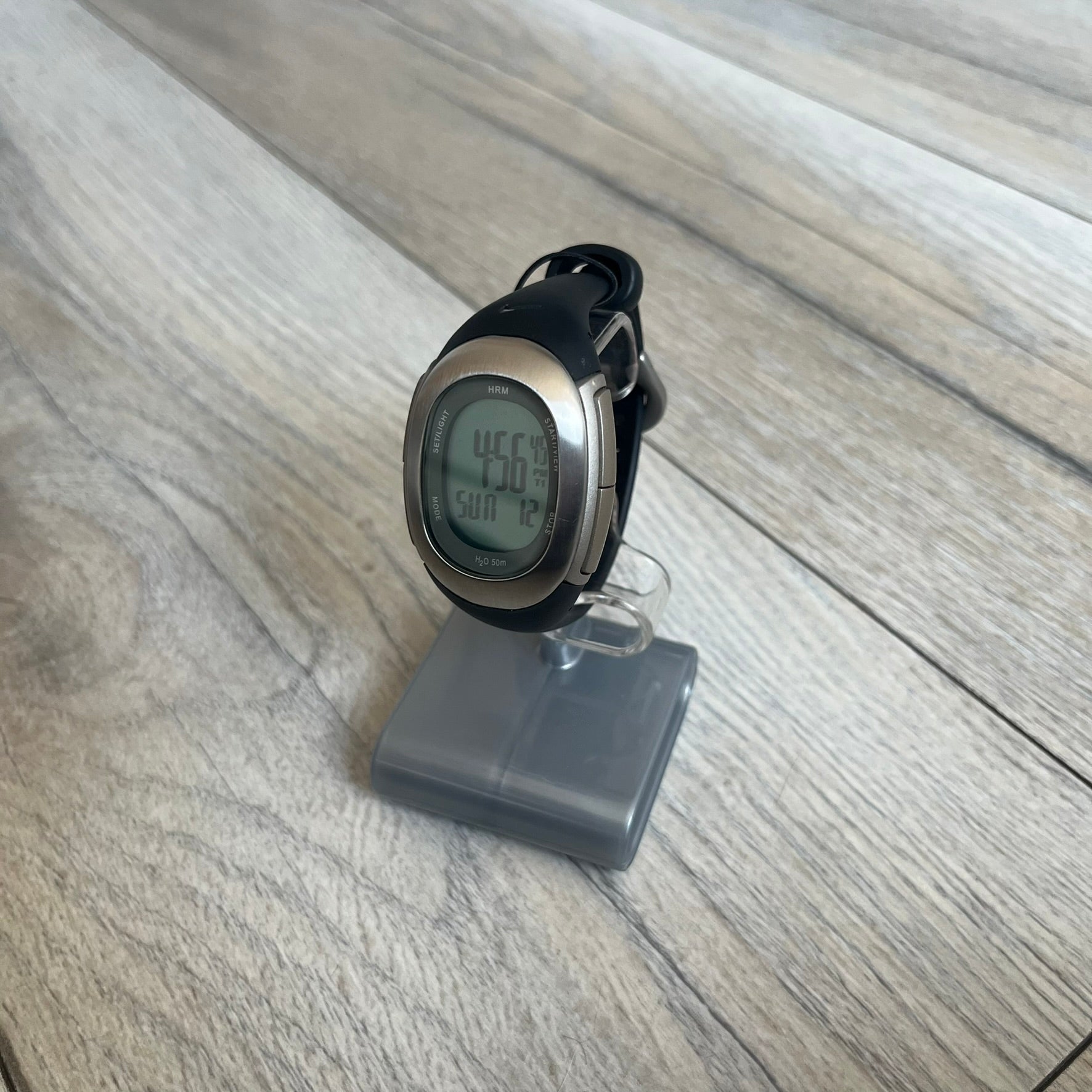 Nike Imara HRM SM0032 Digital Watch is a digital wristwatch featuring a silver case with gray-outlined display and a black rubber strap. The watch includes backlight functionality, multiple modes, and a chest heart rate monitor, with water resistance up to 59 meters. It comes with original box, papers, and a plastic store display.