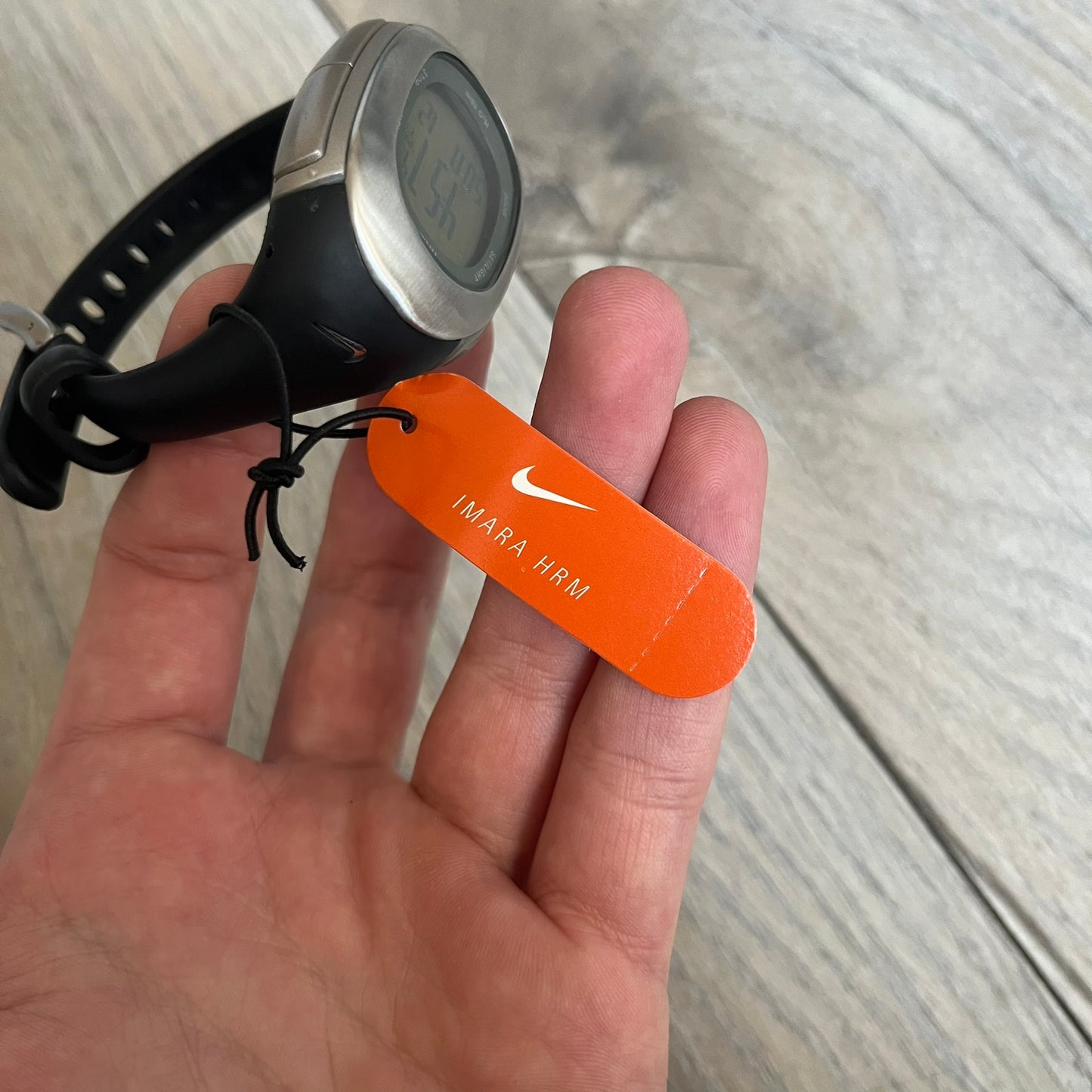 Nike Imara HRM SM0032 Digital Watch is a digital wristwatch featuring a silver case with gray-outlined display and a black rubber strap. The watch includes backlight functionality, multiple modes, and a chest heart rate monitor, with water resistance up to 59 meters. It comes with original box, papers, and a plastic store display.