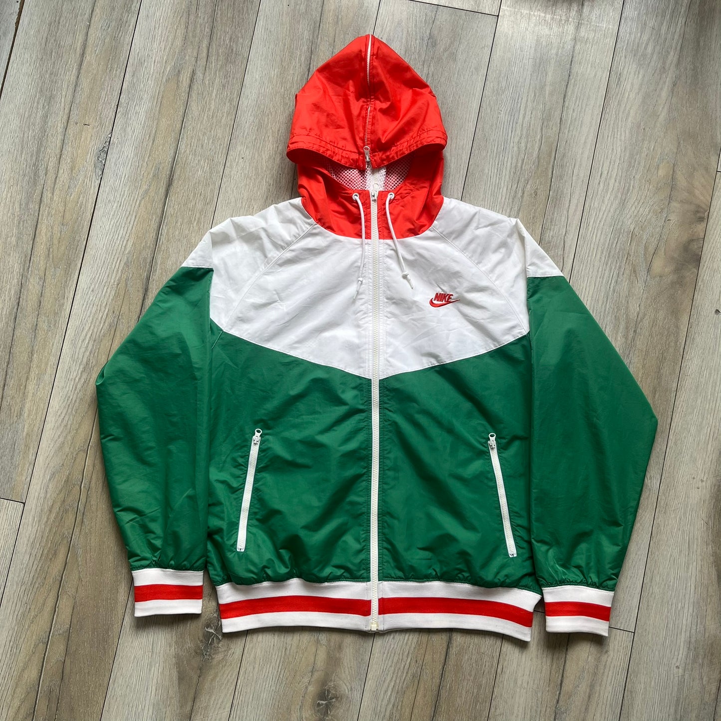 Nike Italy Olympics Split Windbreaker from 2008, created by designer Jarrett Reynolds. Crafted in green/white/red, with a green lower half of the front and sleeves, white upper half and red hood. This innovative jacket can be zipped apart on both sides and merged with other compatible models. Hidden inside, a small Italy flags accent completes the concept.