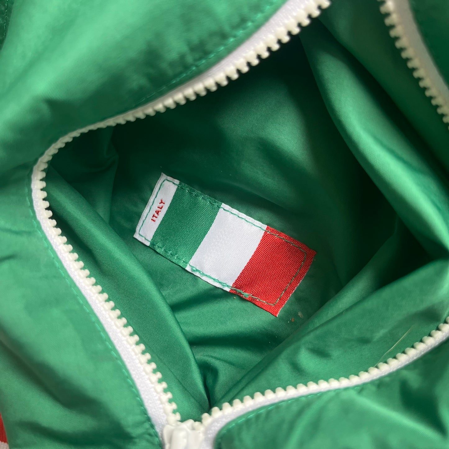Nike Italy Olympics Split Windbreaker from 2008, created by designer Jarrett Reynolds. Crafted in green/white/red, with a green lower half of the front and sleeves, white upper half and red hood. This innovative jacket can be zipped apart on both sides and merged with other compatible models. Hidden inside, a small Italy flags accent completes the concept.