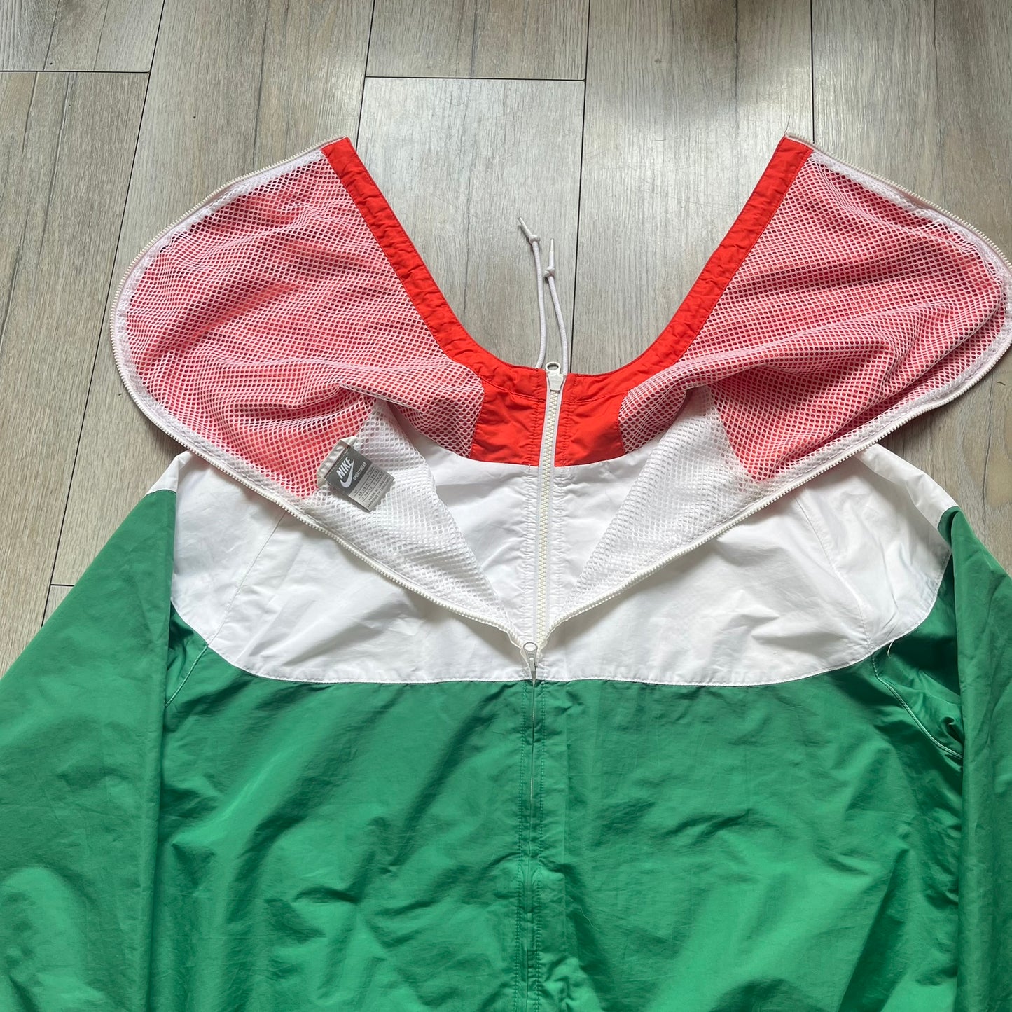Nike Italy Olympics Split Windbreaker from 2008, created by designer Jarrett Reynolds. Crafted in green/white/red, with a green lower half of the front and sleeves, white upper half and red hood. This innovative jacket can be zipped apart on both sides and merged with other compatible models. Hidden inside, a small Italy flags accent completes the concept.