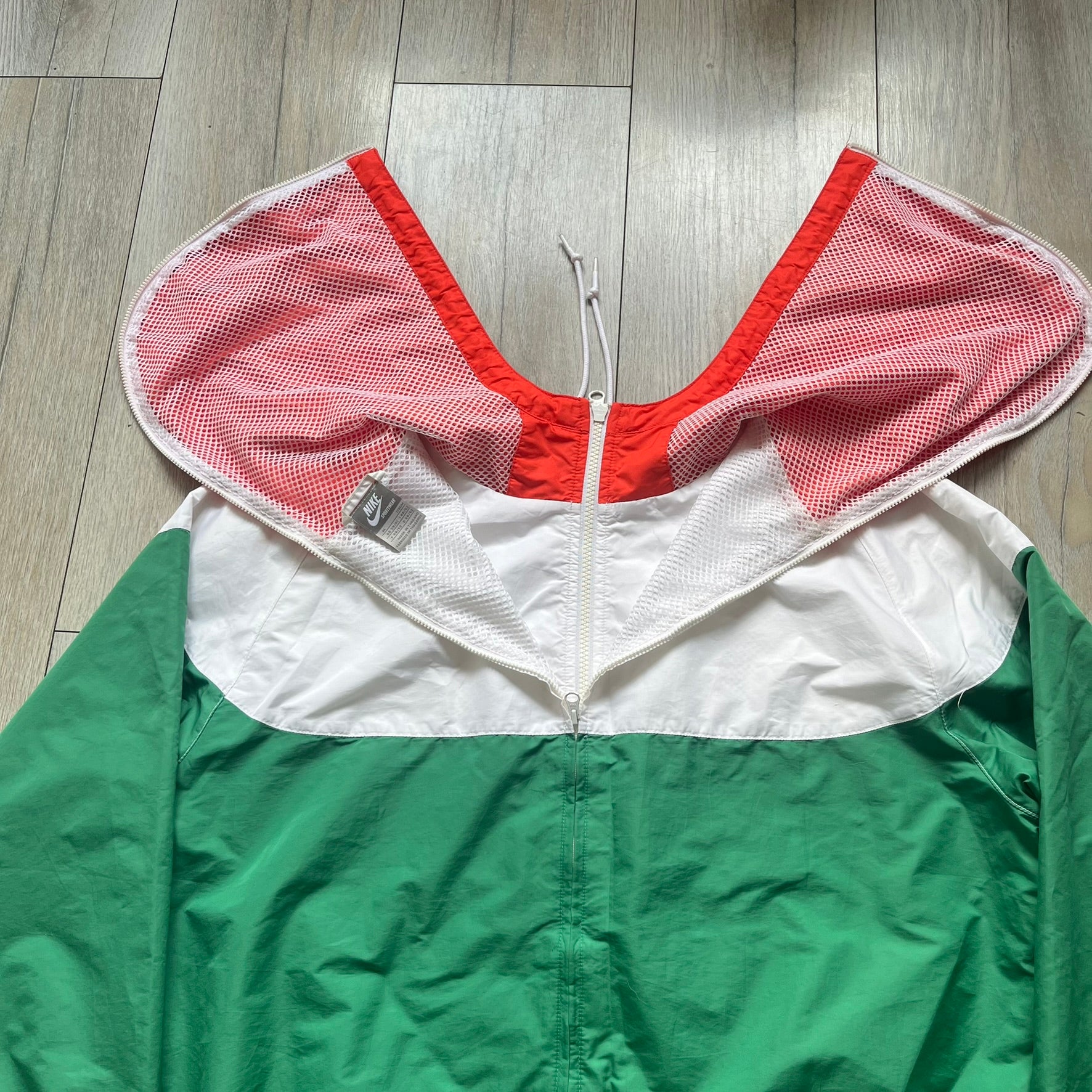 Nike Italy Olympics Split Windbreaker from 2008, created by designer Jarrett Reynolds. Crafted in green/white/red, with a green lower half of the front and sleeves, white upper half and red hood. This innovative jacket can be zipped apart on both sides and merged with other compatible models. Hidden inside, a small Italy flags accent completes the concept.