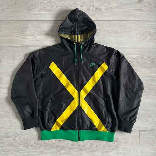 Nike Jamaica Olympics 2008 Split Windbreaker designed by Jarrett Reynolds. Features a black base with a yellow cross on the front inspired by the Jamaican flag. Green bottom hem and details. Dual side zippers allow the jacket to split in half and be combined with other pieces from the collection, with a small Jamaica flag detail inside the pocket.