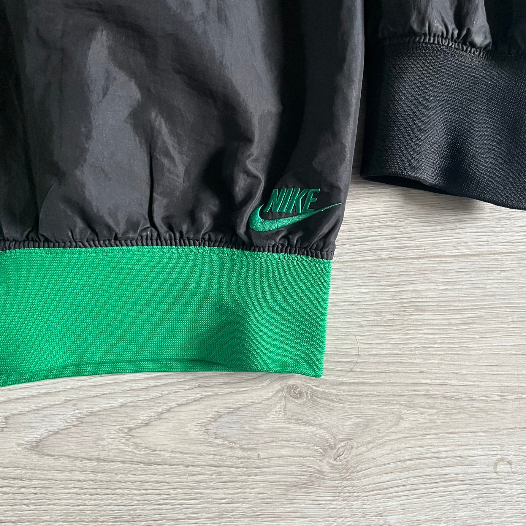 Nike Jamaica Olympics 2008 Split Windbreaker designed by Jarrett Reynolds. Features a black base with a yellow cross on the front inspired by the Jamaican flag. Green bottom hem and details. Dual side zippers allow the jacket to split in half and be combined with other pieces from the collection, with a small Jamaica flag detail inside the pocket.