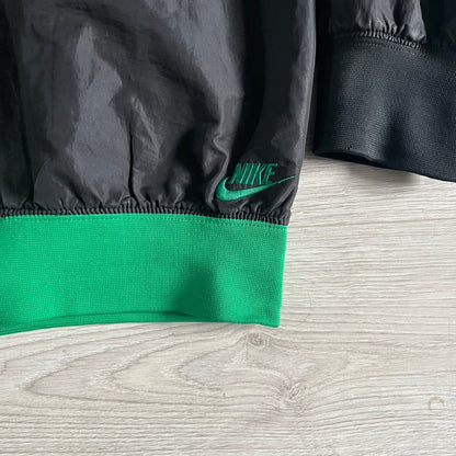 Nike Jamaica Olympics 2008 Split Windbreaker designed by Jarrett Reynolds. Features a black base with a yellow cross on the front inspired by the Jamaican flag. Green bottom hem and details. Dual side zippers allow the jacket to split in half and be combined with other pieces from the collection, with a small Jamaica flag detail inside the pocket.