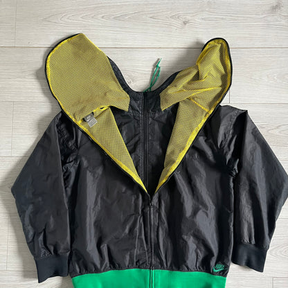 Nike Jamaica Olympics 2008 Split Windbreaker designed by Jarrett Reynolds. Features a black base with a yellow cross on the front inspired by the Jamaican flag. Green bottom hem and details. Dual side zippers allow the jacket to split in half and be combined with other pieces from the collection, with a small Jamaica flag detail inside the pocket.