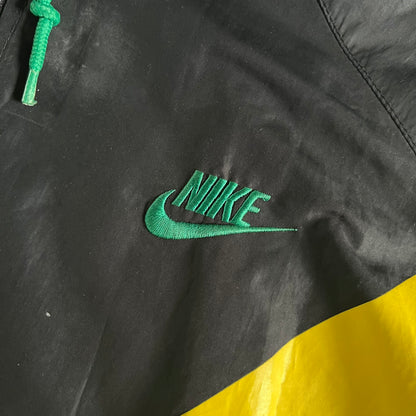 Nike Jamaica Olympics 2008 Split Windbreaker designed by Jarrett Reynolds. Features a black base with a yellow cross on the front inspired by the Jamaican flag. Green bottom hem and details. Dual side zippers allow the jacket to split in half and be combined with other pieces from the collection, with a small Jamaica flag detail inside the pocket.