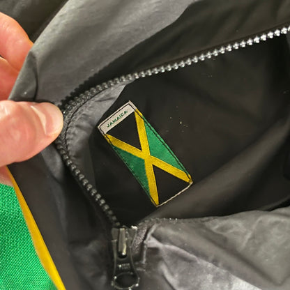 Nike Jamaica Olympics 2008 Split Windbreaker designed by Jarrett Reynolds. Features a black base with a yellow cross on the front inspired by the Jamaican flag. Green bottom hem and details. Dual side zippers allow the jacket to split in half and be combined with other pieces from the collection, with a small Jamaica flag detail inside the pocket.