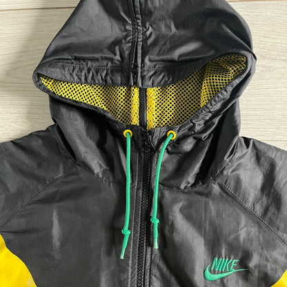 Nike Jamaica Olympics 2008 Split Windbreaker designed by Jarrett Reynolds. Features a black base with a yellow cross on the front inspired by the Jamaican flag. Green bottom hem and details. Dual side zippers allow the jacket to split in half and be combined with other pieces from the collection, with a small Jamaica flag detail inside the pocket.