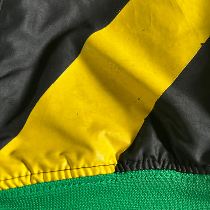 Nike Jamaica Olympics 2008 Split Windbreaker designed by Jarrett Reynolds. Features a black base with a yellow cross on the front inspired by the Jamaican flag. Green bottom hem and details. Dual side zippers allow the jacket to split in half and be combined with other pieces from the collection, with a small Jamaica flag detail inside the pocket.