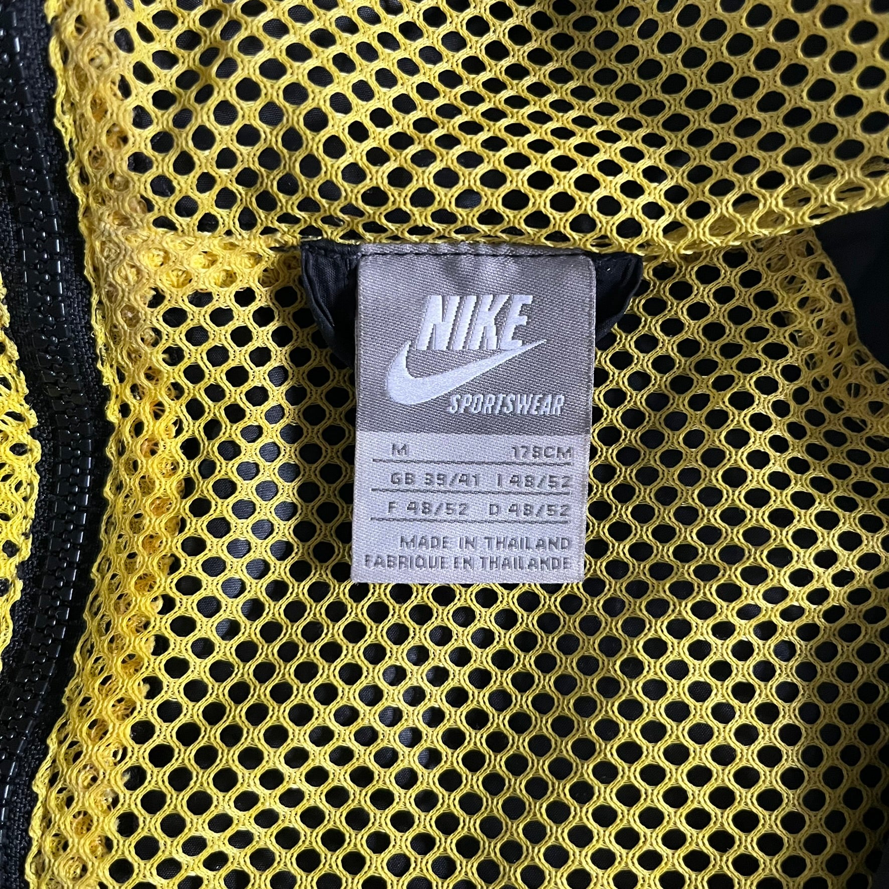 Nike Jamaica Olympics 2008 Split Windbreaker designed by Jarrett Reynolds. Features a black base with a yellow cross on the front inspired by the Jamaican flag. Green bottom hem and details. Dual side zippers allow the jacket to split in half and be combined with other pieces from the collection, with a small Jamaica flag detail inside the pocket.