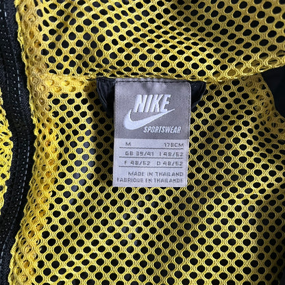 Nike Jamaica Olympics 2008 Split Windbreaker designed by Jarrett Reynolds. Features a black base with a yellow cross on the front inspired by the Jamaican flag. Green bottom hem and details. Dual side zippers allow the jacket to split in half and be combined with other pieces from the collection, with a small Jamaica flag detail inside the pocket.