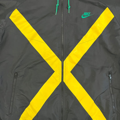 Nike Jamaica Olympics 2008 Split Windbreaker designed by Jarrett Reynolds. Features a black base with a yellow cross on the front inspired by the Jamaican flag. Green bottom hem and details. Dual side zippers allow the jacket to split in half and be combined with other pieces from the collection, with a small Jamaica flags detail inside the pocket.