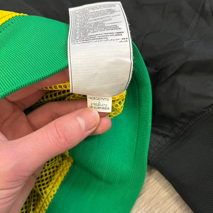 Nike Jamaica Olympics 2008 Split Windbreaker designed by Jarrett Reynolds. Features a black base with a yellow cross on the front inspired by the Jamaican flag. Green bottom hem and details. Dual side zippers allow the jacket to split in half and be combined with other pieces from the collection, with a small Jamaica flags detail inside the pocket.