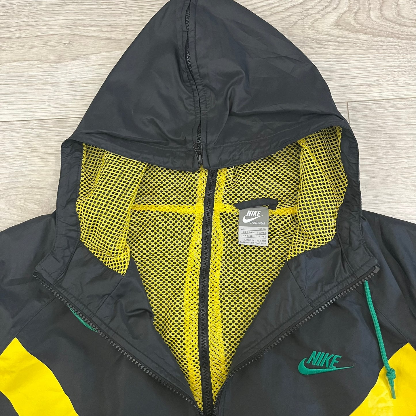 Nike Jamaica Olympics 2008 Split Windbreaker designed by Jarrett Reynolds. Features a black base with a yellow cross on the front inspired by the Jamaican flag. Green bottom hem and details. Dual side zippers allow the jacket to split in half and be combined with other pieces from the collection, with a small Jamaica flags detail inside the pocket.