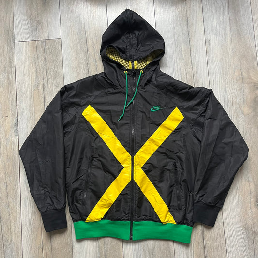 Nike Jamaica Olympics 2008 Split Windbreaker designed by Jarrett Reynolds. Features a black base with a yellow cross on the front inspired by the Jamaican flag. Green bottom hem and details. Dual side zippers allow the jacket to split in half and be combined with other pieces from the collection, with a small Jamaica flags detail inside the pocket.