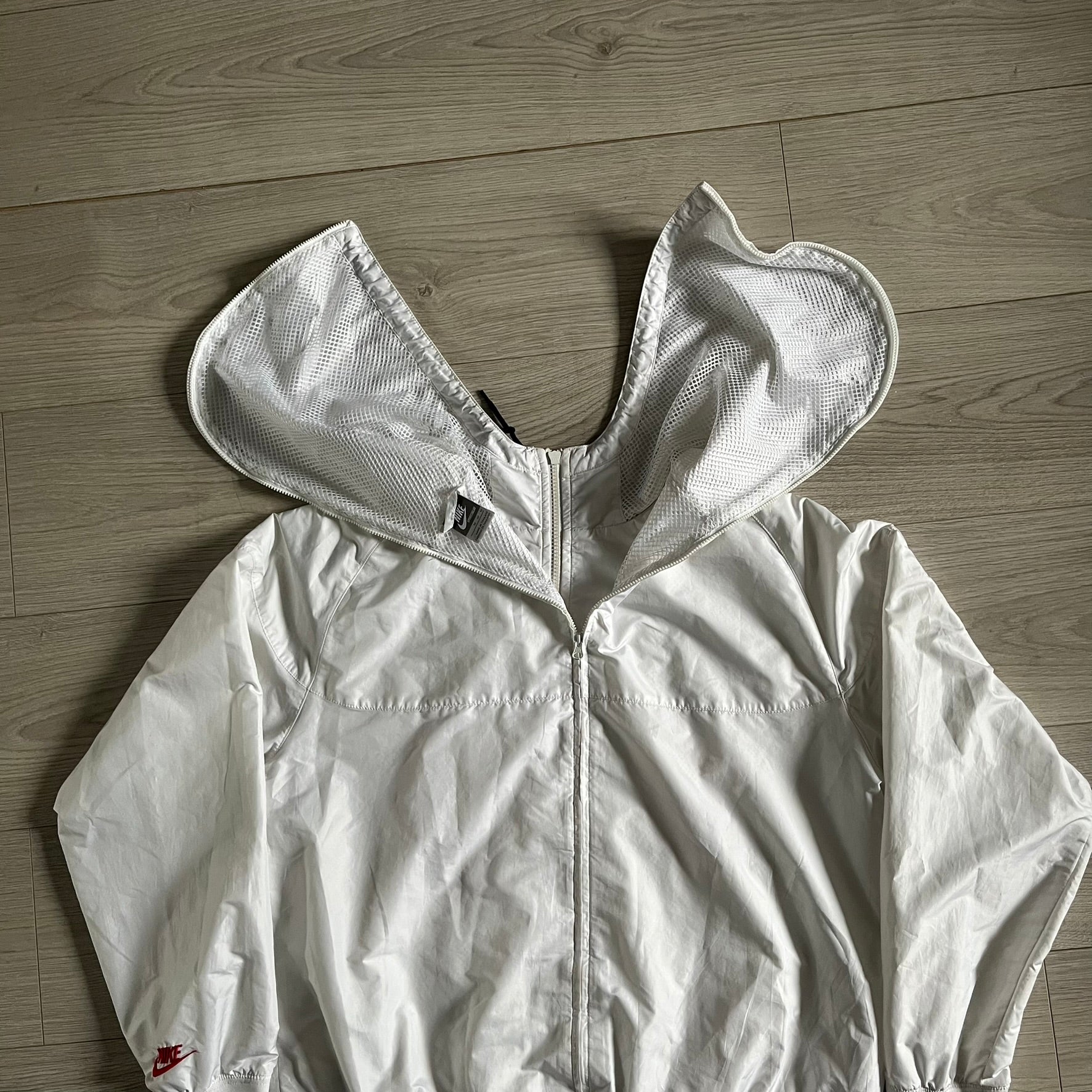 Nike Japan Olympics Split Windbreaker from 2008, created by designer Jarrett Reynolds. Crafted in white with a large red circle representing Japan’s flag, this innovative jacket can be zipped apart on both sides and merged with other compatible models. Hidden inside, a small Japan flag accent completes the concept.
