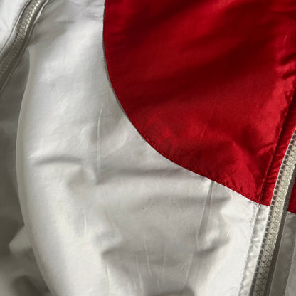 Nike Japan Olympics Split Windbreaker from 2008, created by designer Jarrett Reynolds. Crafted in white with a large red circle representing Japan’s flag, this innovative jacket can be zipped apart on both sides and merged with other compatible models. Hidden inside, a small Japan flag accent completes the concept.
