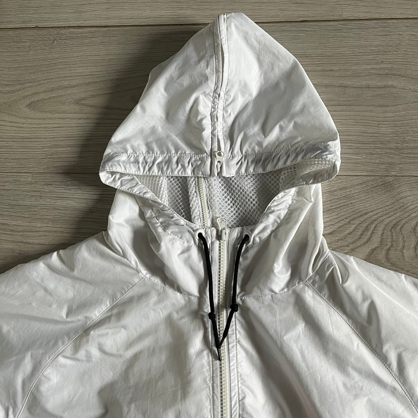 Nike Japan Olympics Split Windbreaker from 2008, created by designer Jarrett Reynolds. Crafted in white with a large red circle representing Japan’s flag, this innovative jacket can be zipped apart on both sides and merged with other compatible models. Hidden inside, a small Japan flag accent completes the concept.