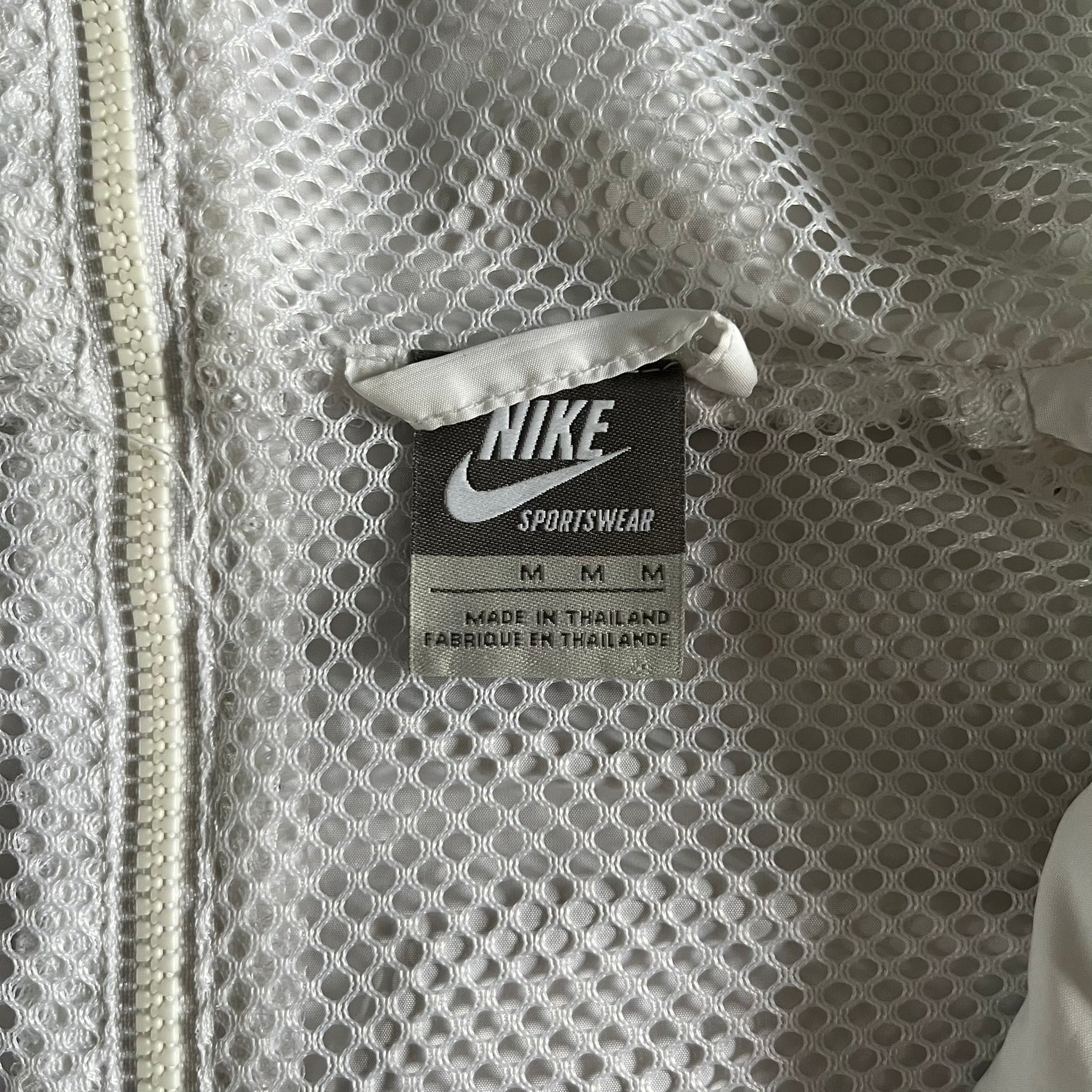 Nike Japan Olympics Split Windbreaker from 2008, created by designer Jarrett Reynolds. Crafted in white with a large red circle representing Japan’s flag, this innovative jacket can be zipped apart on both sides and merged with other compatible models. Hidden inside, a small Japan flag accent completes the concept.