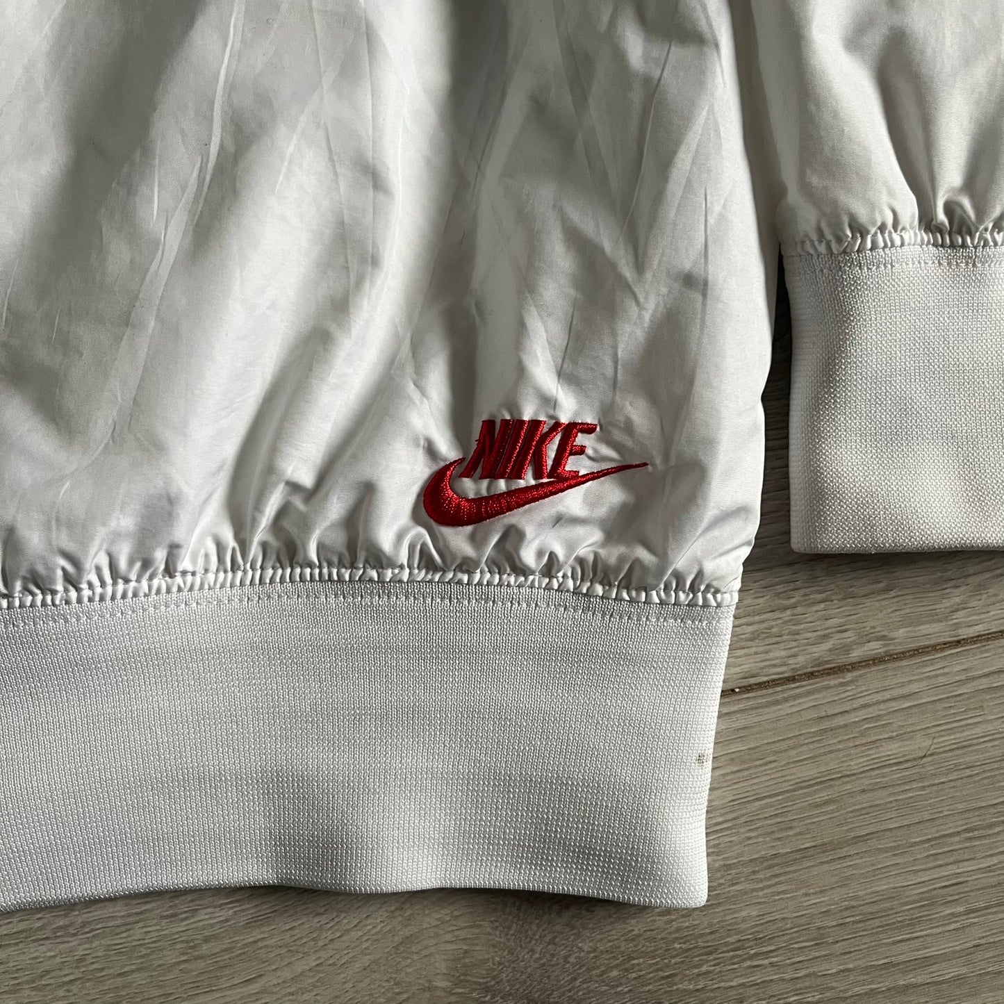 Nike Japan Olympics Split Windbreaker from 2008, created by designer Jarrett Reynolds. Crafted in white with a large red circle representing Japan’s flag, this innovative jacket can be zipped apart on both sides and merged with other compatible models. Hidden inside, a small Japan flag accent completes the concept.