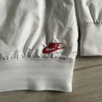 Nike Japan Olympics Split Windbreaker from 2008, created by designer Jarrett Reynolds. Crafted in white with a large red circle representing Japan’s flag, this innovative jacket can be zipped apart on both sides and merged with other compatible models. Hidden inside, a small Japan flag accent completes the concept.