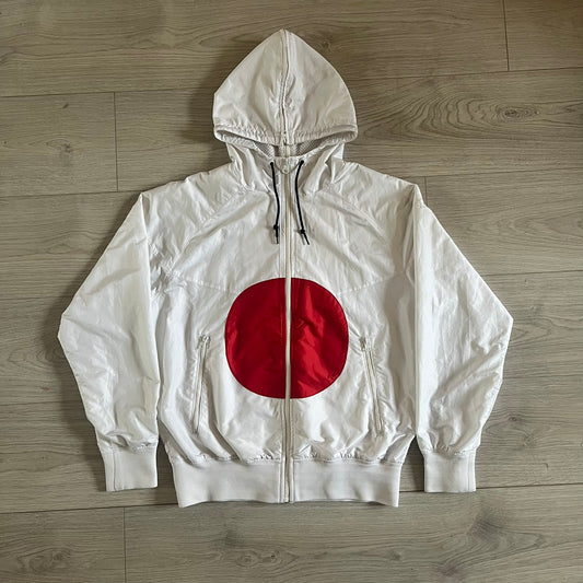 Nike Japan Olympics Split Windbreaker from 2008, created by designer Jarrett Reynolds. Crafted in white with a large red circle representing Japan’s flag, this innovative jacket can be zipped apart on both sides and merged with other compatible models. Hidden inside, a small Japan flags accent completes the concept.