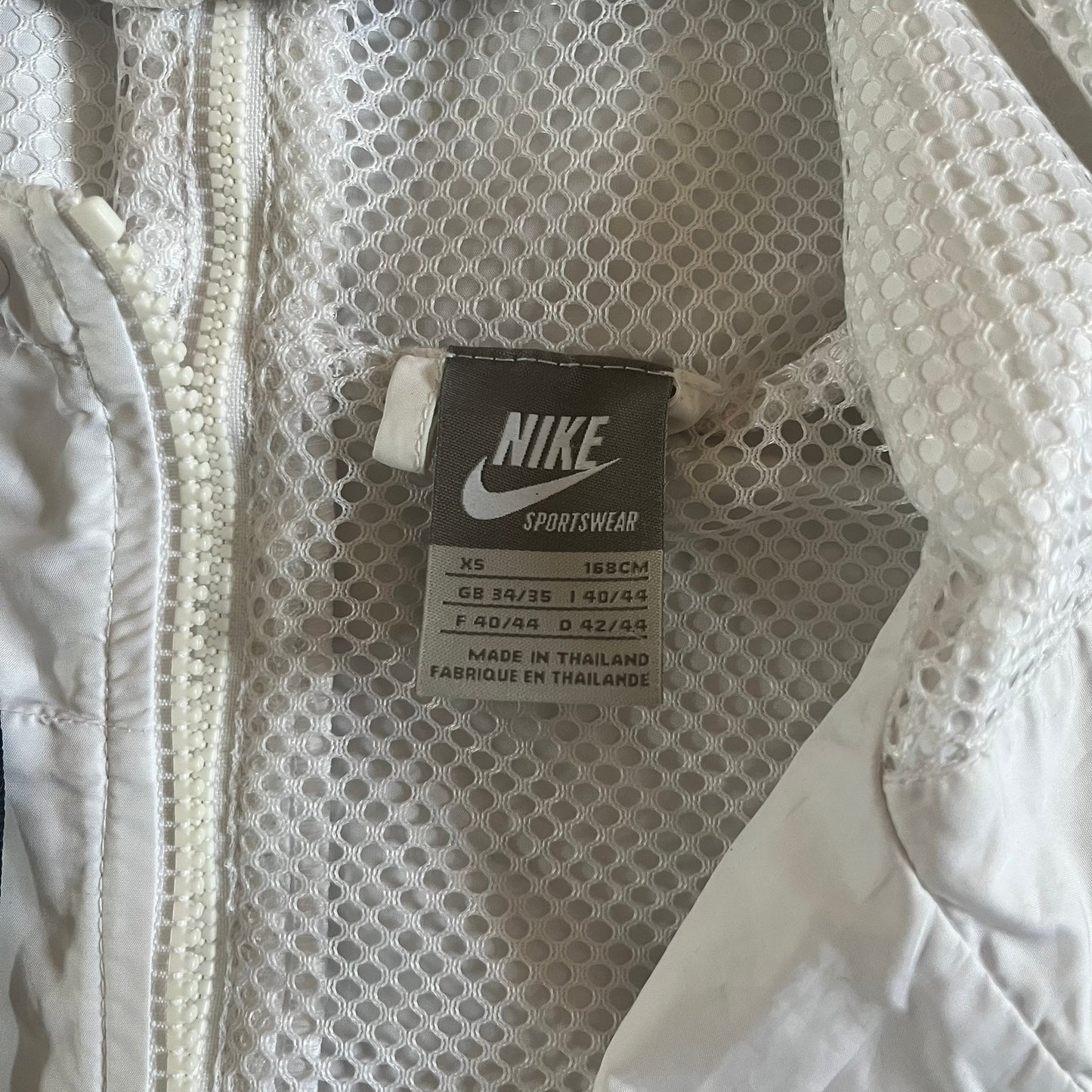 Nike Japan Olympics Split Windbreaker from 2008, created by designer Jarrett Reynolds. Crafted in white with a large red circle representing Japan’s flag, this innovative jacket can be zipped apart on both sides and merged with other compatible models. Hidden inside, a small Japan flags accent completes the concept.