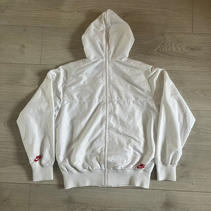 Nike Japan Olympics Split Windbreaker from 2008, created by designer Jarrett Reynolds. Crafted in white with a large red circle representing Japan’s flag, this innovative jacket can be zipped apart on both sides and merged with other compatible models. Hidden inside, a small Japan flags accent completes the concept.