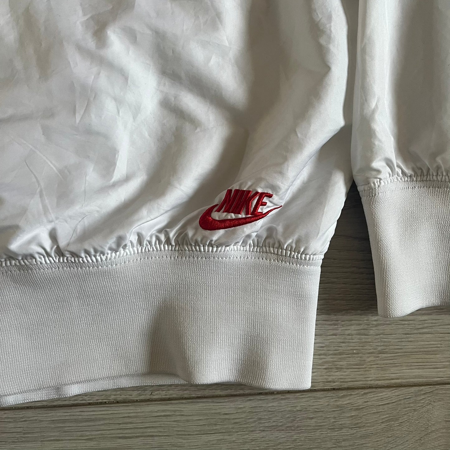 Nike Japan Olympics Split Windbreaker from 2008, created by designer Jarrett Reynolds. Crafted in white with a large red circle representing Japan’s flag, this innovative jacket can be zipped apart on both sides and merged with other compatible models. Hidden inside, a small Japan flags accent completes the concept.