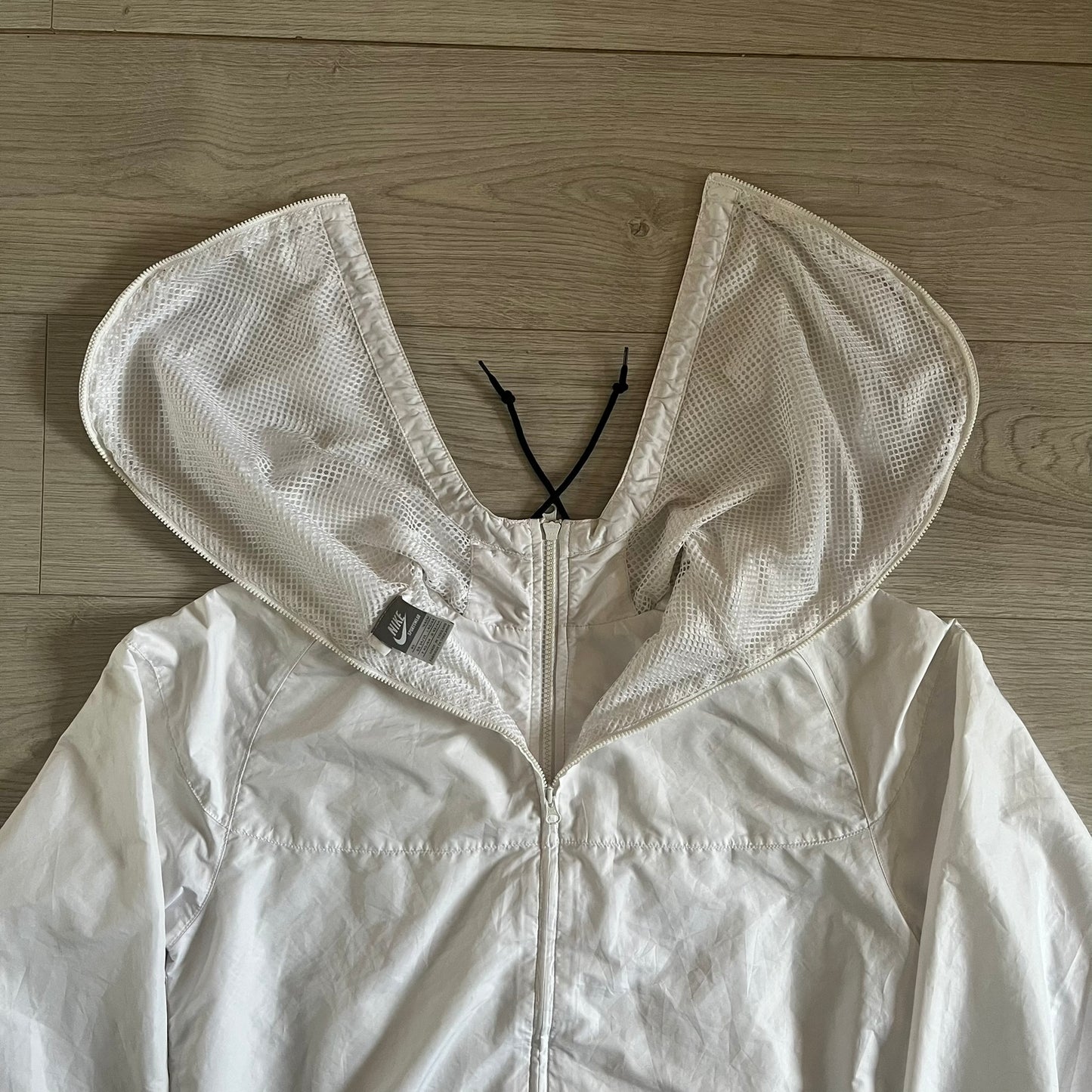 Nike Japan Olympics Split Windbreaker from 2008, created by designer Jarrett Reynolds. Crafted in white with a large red circle representing Japan’s flag, this innovative jacket can be zipped apart on both sides and merged with other compatible models. Hidden inside, a small Japan flags accent completes the concept.